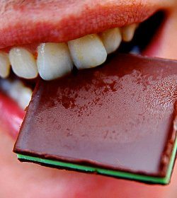 Close up picture of a person biting a block of chocolate
