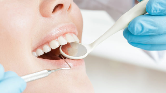 Dental abscess information feature image of patient with dentist looking at teeth using dental tools