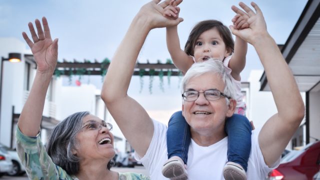 image of 2 grandparents with the a little girl on their shoulders